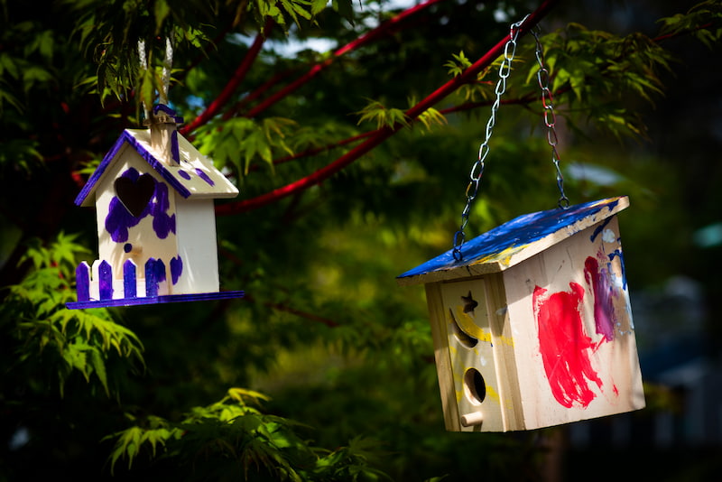 Homemade, hand painted childrens' bird houses hanging in a tree