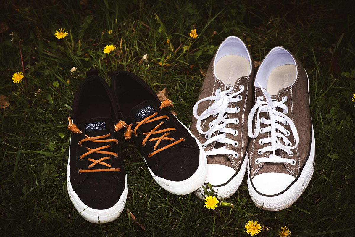 A pair of converse and Sperry's next to each other in the grass.