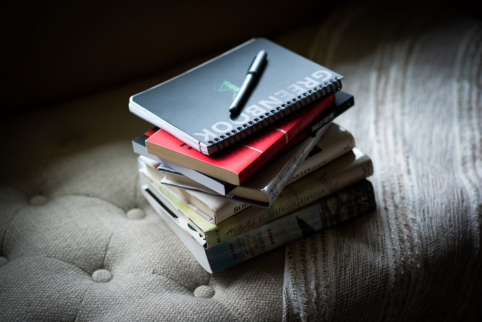 Stack of books with a journal and pen on the top.