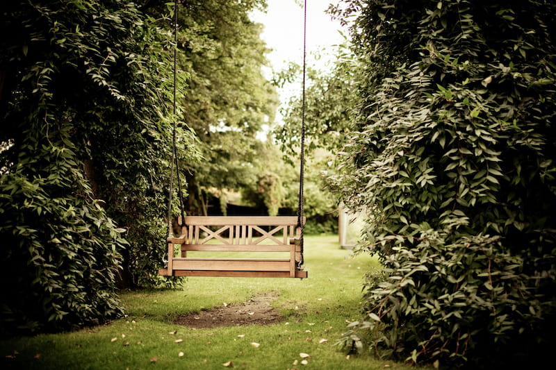 Hanging swinging bench in the center of a garden.